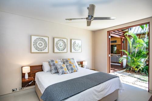 a bedroom with a bed with a ceiling fan at Niramaya Villas and Spa in Port Douglas