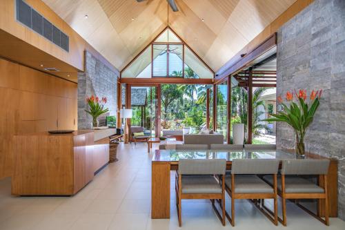 uma cozinha em plano aberto e sala de jantar com uma mesa de vidro e cadeiras em Niramaya Villas and Spa em Port Douglas