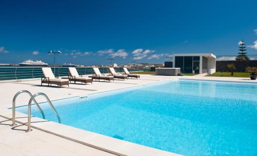 a swimming pool with lounge chairs on a building at Atlantida Mar Hotel in Praia da Vitória