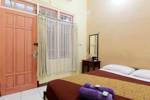a bedroom with a bed and a door and a window at Monica Hotel in Yogyakarta