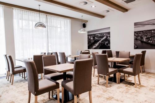 a conference room with tables and chairs and a painting at Hotel Platan in Gdańsk