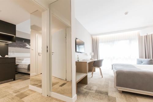 a bedroom with a bed and a desk and a mirror at Hotel Platan in Gdańsk