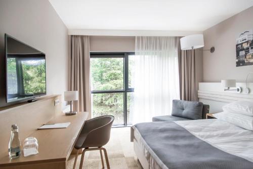 a hotel room with a bed and a desk and a window at Hotel Platan in Gdańsk