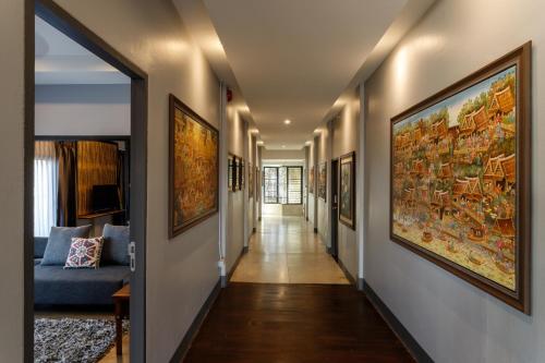 a hallway with paintings on the walls and a blue couch at Hostel One Art and Gallery in Chiang Mai