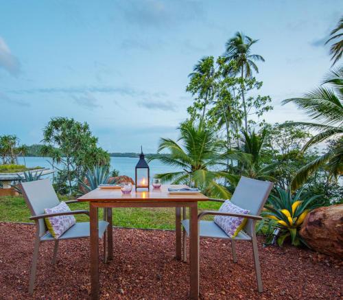 a wooden table with two chairs and a candle on it at Tri by Amaya in Ahangama