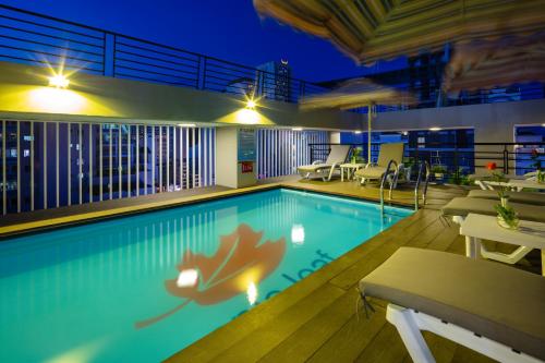 a swimming pool with tables and chairs on a building at Maple Leaf Hotel & Apartment in Nha Trang