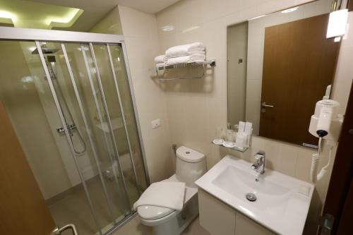 a bathroom with a shower and a toilet and a sink at Justice Hotel in Bangkok