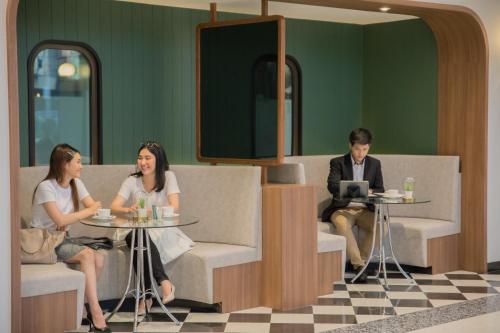 two women and a man sitting at a table with a laptop at Justice Hotel in Bangkok