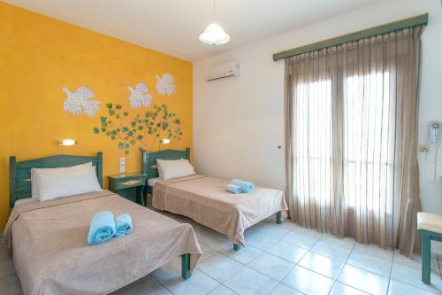 two beds in a room with yellow walls at Stefanis House in Skiathos Town