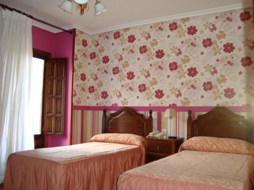 a bedroom with two beds and a floral wallpaper at Hosteria Peña Sagra in Ojedo