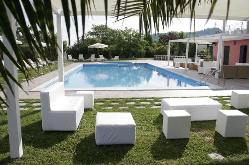 a swimming pool with white chairs and a swimming pool at Country Hotel & Resort I Calanchi in Ripatransone