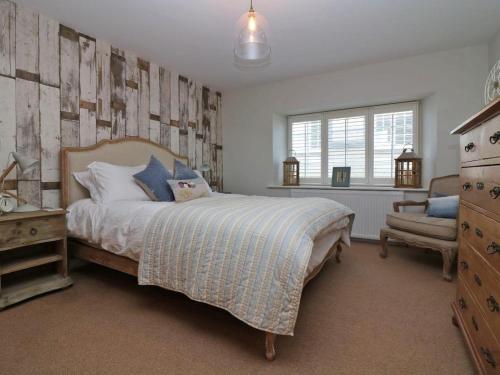 a bedroom with a bed and a dresser and a window at Trelan in St Austell