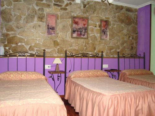 a bedroom with two beds and a stone wall at Hosteria Peña Sagra in Ojedo