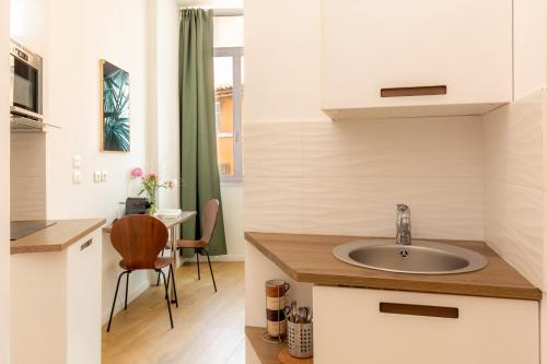 une cuisine avec un évier et une table avec une chaise dans l'établissement Breteuil – Appart au Vieux Port, à Marseille