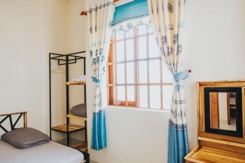 Habitación con una ventana con cortinas azules y blancas. en Nai's house - Homestay, en Thanh Hải