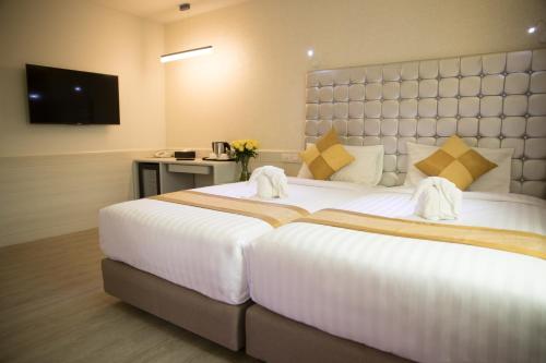 a large white bed in a room with a television at Justice Hotel in Bangkok