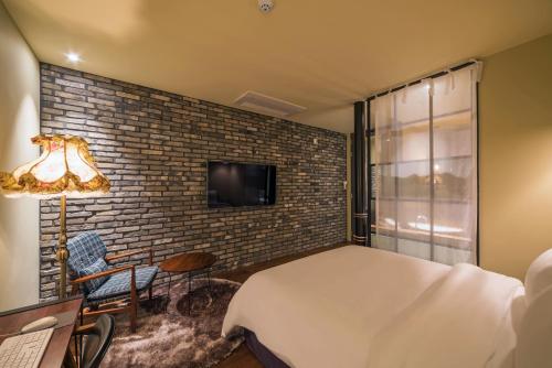 a bedroom with a brick wall and a bed and a tv at Hotel March in Daejeon