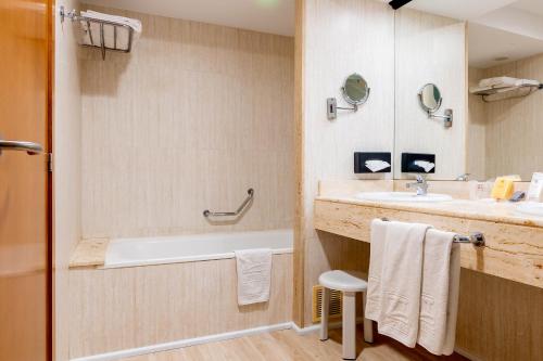 a bathroom with a bath tub and a sink at Peñiscola Plaza Suites in Peniscola