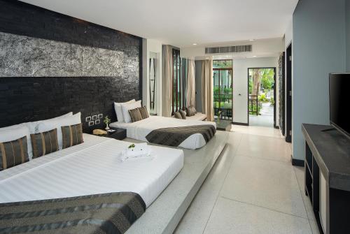 two beds in a hotel room with a television at The Zign Hotel Premium Villa in North Pattaya