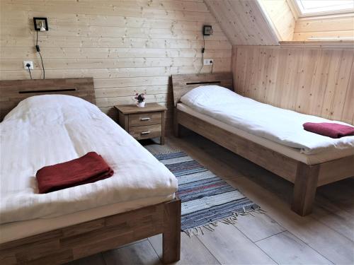 two beds in a room with wooden walls at Kiviranna puhkemajad in Suure-Rakke