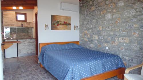 a bedroom with a blue bed and a stone wall at Paraktio Beach Apartments in Kiotari