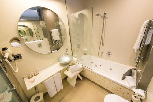 a bathroom with a shower and a sink and a mirror at Hotel & Spa Princesa Munia in Oviedo