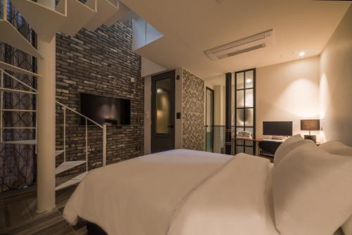 a bedroom with a white bed and a brick wall at Hotel March in Daejeon