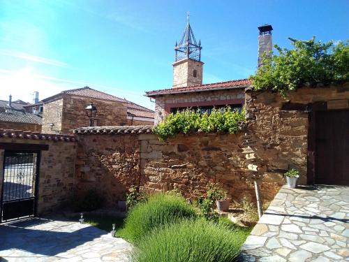 a building with a stone wall with plants on it at La Posada de Toribia in Val de San Lorenzo