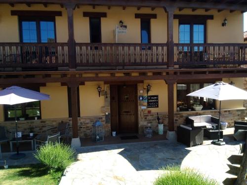 a patio with umbrellas in front of a building at La Posada de Toribia in Val de San Lorenzo