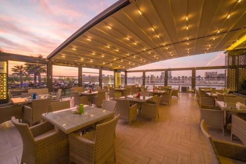 a restaurant with tables and chairs and a view at Golden Tulip Al Khobar Suites in Al Khobar