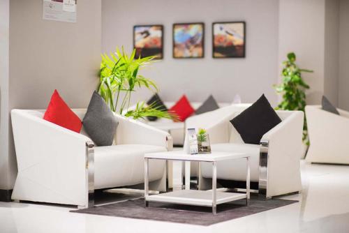 a living room with white couches and a table at Golden Tulip Al Khobar Suites in Al Khobar