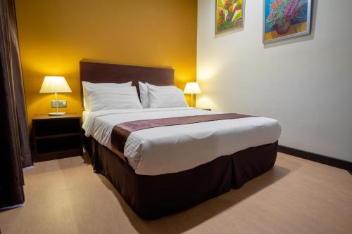 a bedroom with a large bed with two lamps at Orkid Inn Mahkota Cheras in Kampong Perimbun
