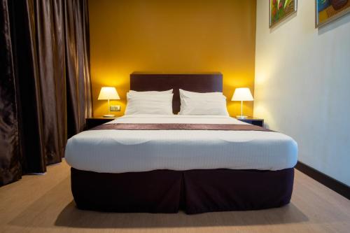 a large bed in a room with two lamps at Orkid Inn Mahkota Cheras in Kampong Perimbun