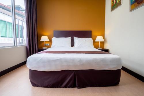 a large bed in a hotel room with two lamps at Orkid Inn Mahkota Cheras in Kampong Perimbun
