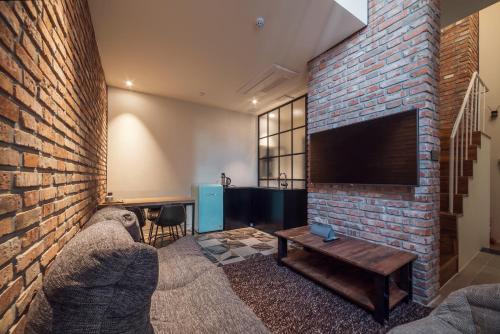 a living room with a brick wall and a tv at Hotel March in Daejeon