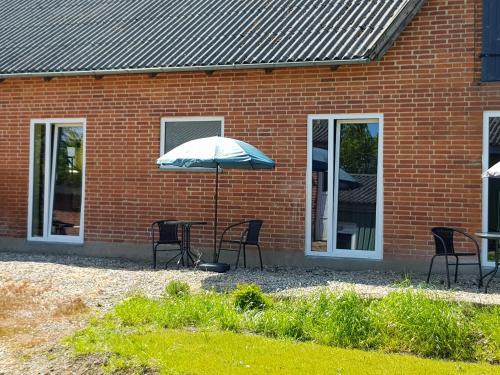 a table and chairs with an umbrella in front of a brick building at Kyndestoft Bed & Breakfast in Holstebro