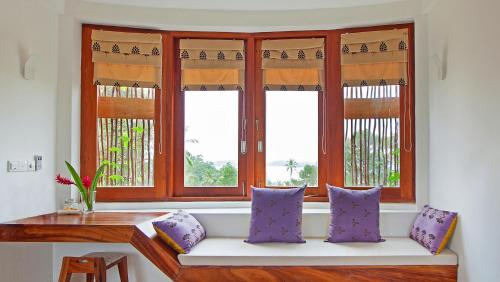 a window seat in a room with purple pillows at Tri by Amaya in Ahangama