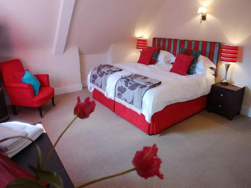 Un dormitorio con una cama y una silla roja. en Maristow Barton, en Plymouth