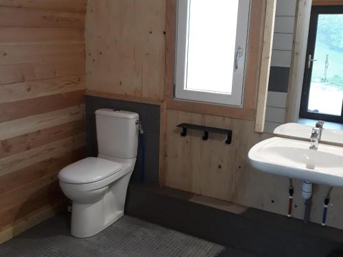 a bathroom with a toilet and a sink at Domaine de l'Ours / Camping Lodge in Saint-Urcize