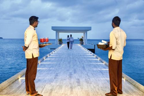 two men standing on a dock in the ocean at Riu Palace Maldivas- All Inclusive in Dhaalu Atoll