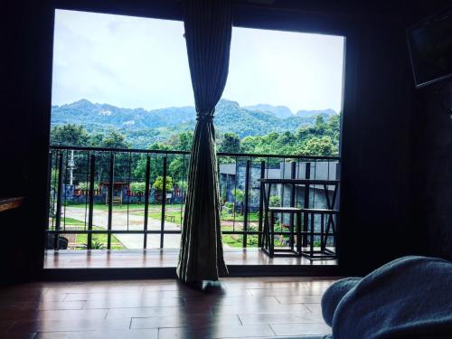a room with a large window with a view of mountains at Keeree Loft Resort คีรีลอฟท์รีสอร์ท in Thong Pha Phum