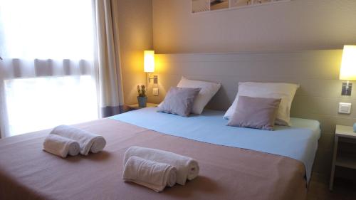 een slaapkamer met een groot wit bed en handdoeken bij VVF Île de Ré Sainte-Marie-de-Ré in Sainte-Marie-de-Ré