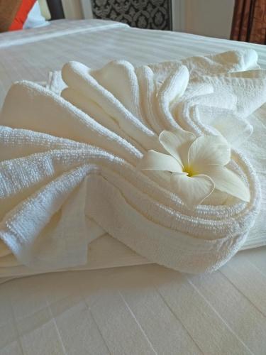 a white towel with a flower on a bed at The Ford SunSet Beach Resort in Wok Tum