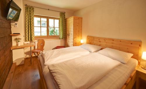 a bedroom with a bed and a desk and a window at Blasiwirt in Sankt Michael im Lungau