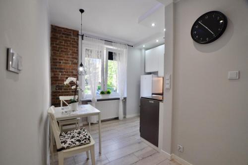 a kitchen with a table and a clock on the wall at Apartament Grey in Busko-Zdrój