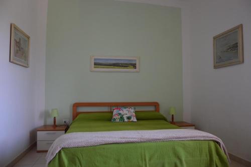 a bedroom with a green bed and two pictures on the wall at Monica appartamenti in San Vincenzo