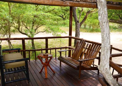 a porch with two wooden chairs and a table at Pezulu Tree House Lodge in Hoedspruit