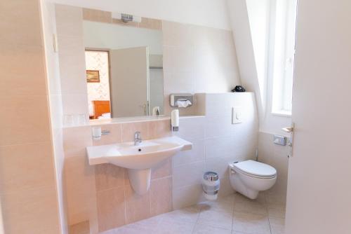 a bathroom with a sink and a toilet and a mirror at Walzer Hotel in Budapest