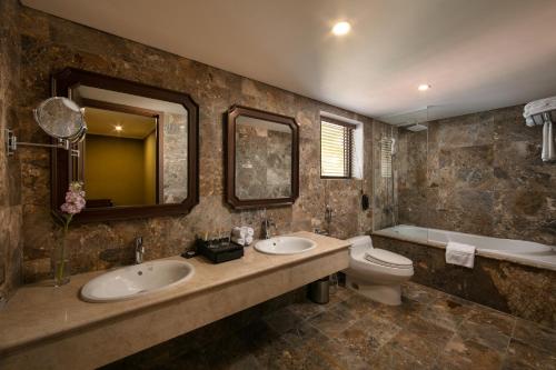 a bathroom with two sinks and a toilet and a tub at Pistachio Hotel Sapa in Sa Pa