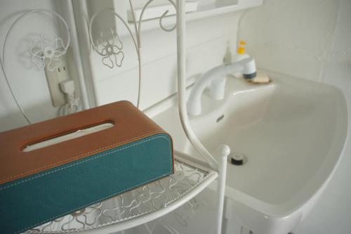 a bathroom with a sink and a purse on a shelf at Guest House Japan Heart in Hokuto